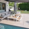 Moderne weiße Aluminium Lounge Cannes weiß Teak von ICM Gartenlounge an einem luxuriösen Pool, dekoriert mit Kissen und Tischdeko. ICM Gartenlounge Cannes Aluminium weiß Pool.