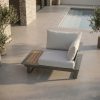 Sessel mit integriertem Tischmodul Einzelsessel mit integriertem Tisch, Gestell in Anthrazit und Tischplatte in Teak, auf einer Terrasse platziert.